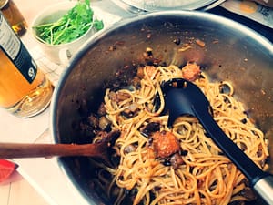 Ein großer Edelstahltopf mit den nudeln gemäß Rezept, daneben eine Flasche mit Balsamico Bianco und eine Schale Rucola