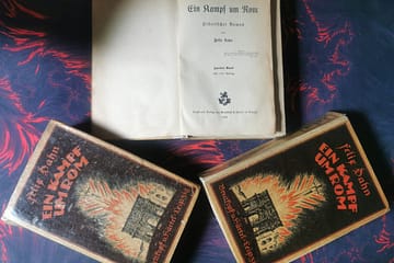 Drei alte Bücher mit dem Titel "Ein Kampf um Rom" von dem Autor Felix Dahn, eines davon aufgeschlagen auf der ersten Seite.