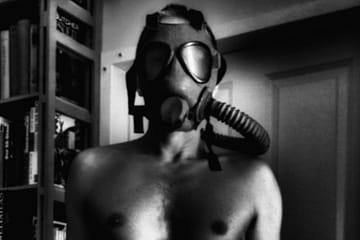 the upper torso and head of a man with an old breathing mask and hose.